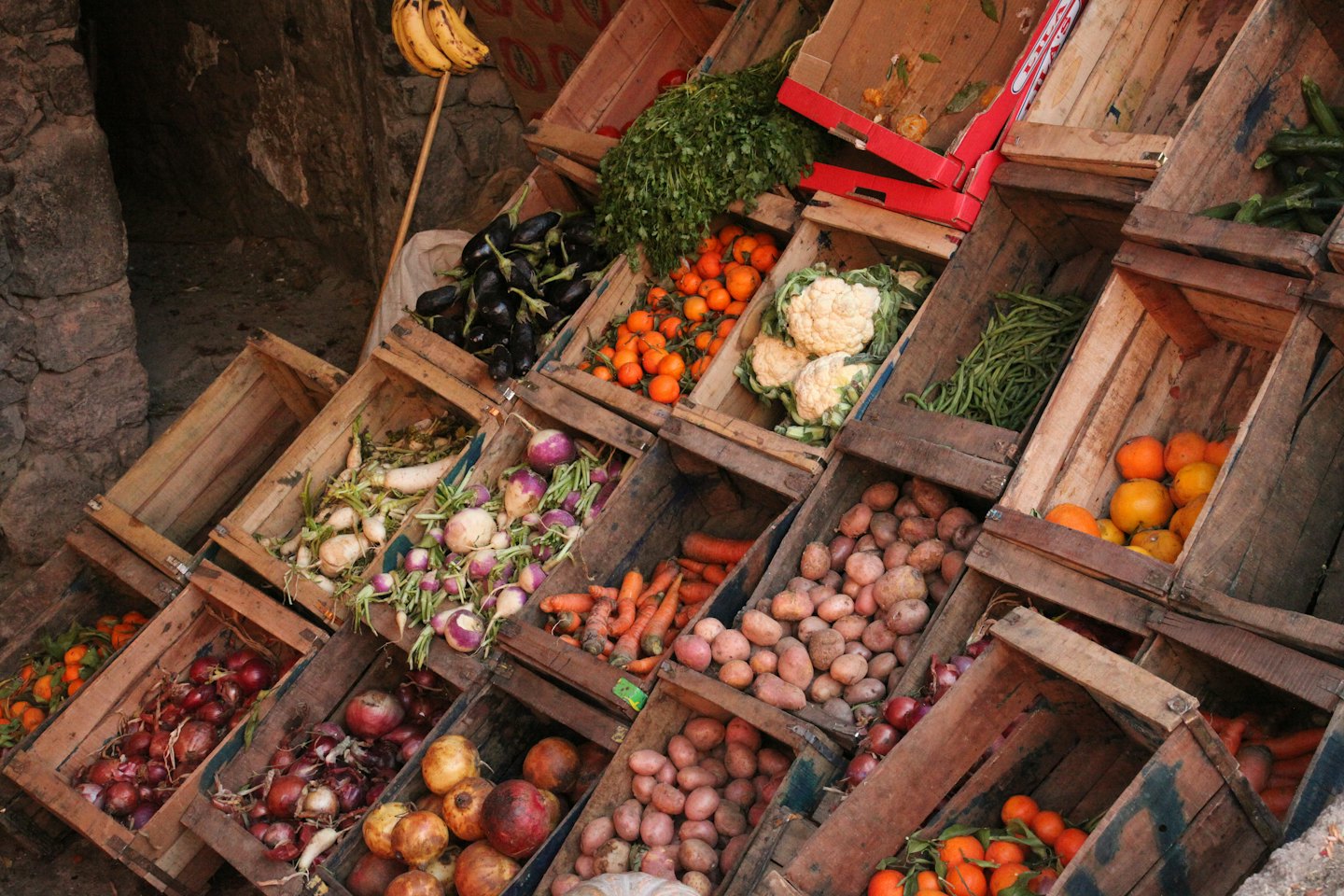 Fresh fruits and vegetables are displayed in wooden market crates.